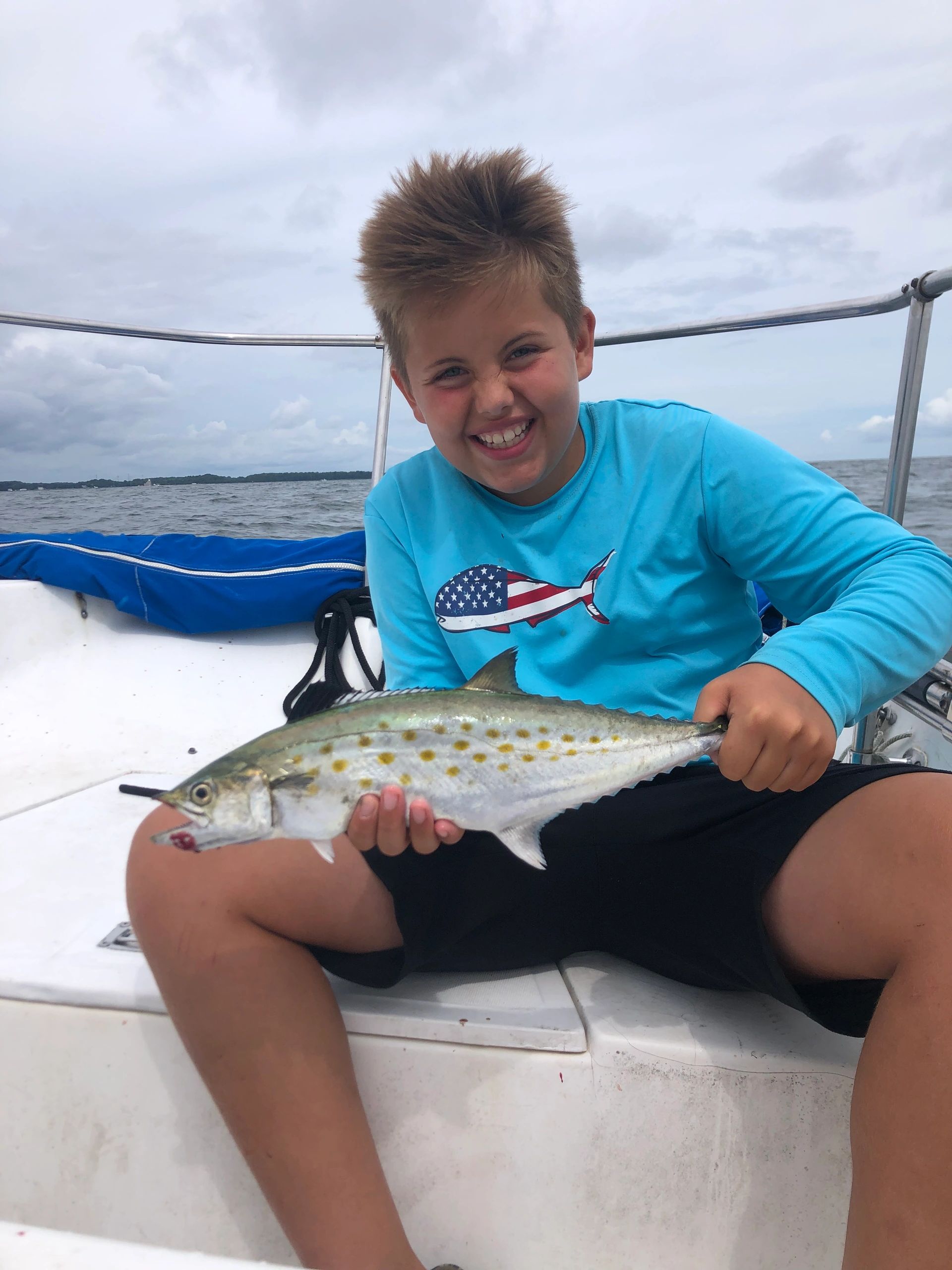 Boy holding fish on fishing boat in summer