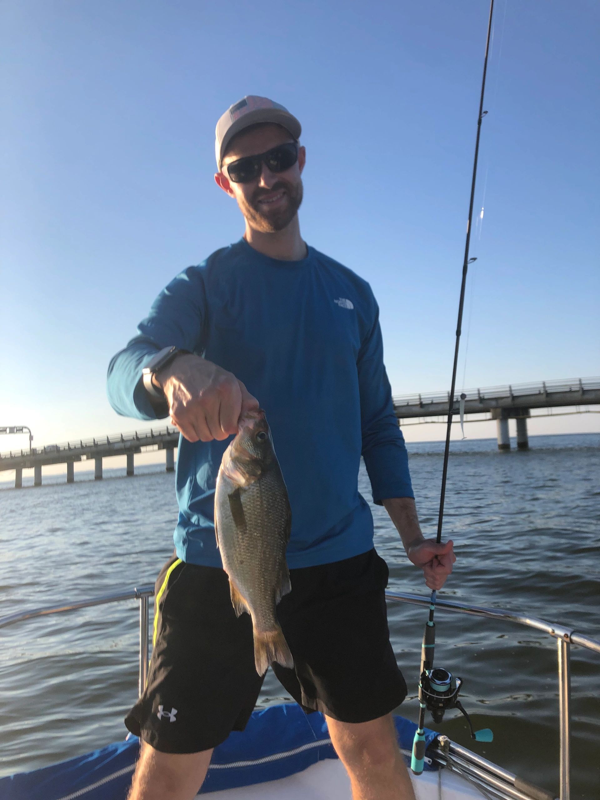 Man holding fish with bridge in background